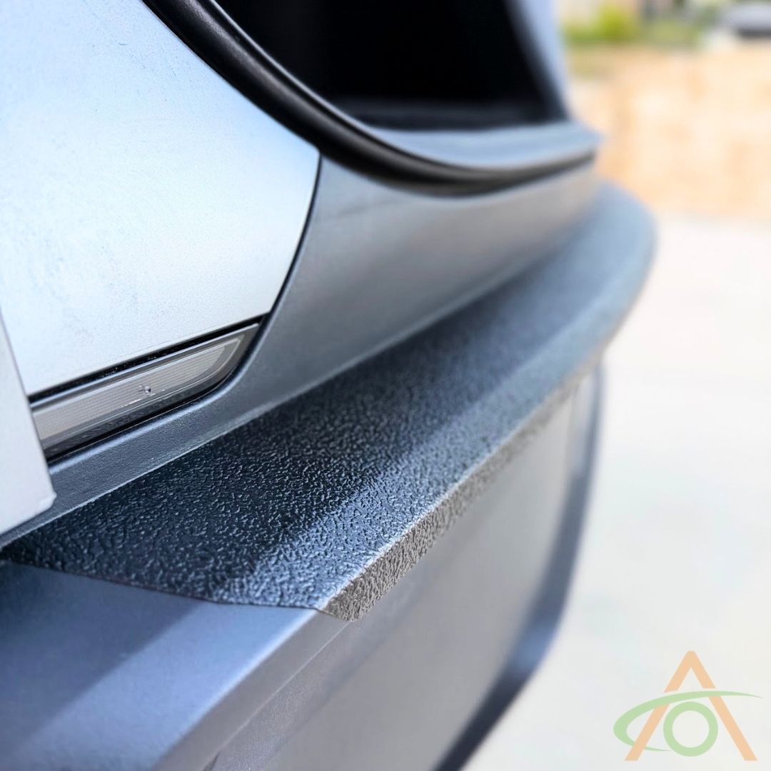 Close-up of the textured satin black XPEL Armor wrapping the rear bumper edge on a Model Y Juniper