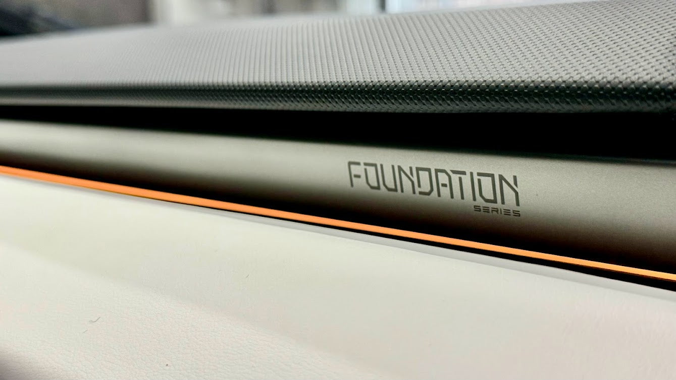 Close-up of the Foundation Series badge etched into the dashboard trim of a Tesla Cybertruck, with the orange accent line below it