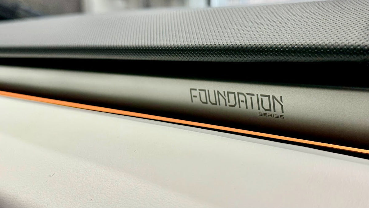 Close-up of the Foundation Series badge etched into the dashboard trim of a Tesla Cybertruck, with the orange accent line below it
